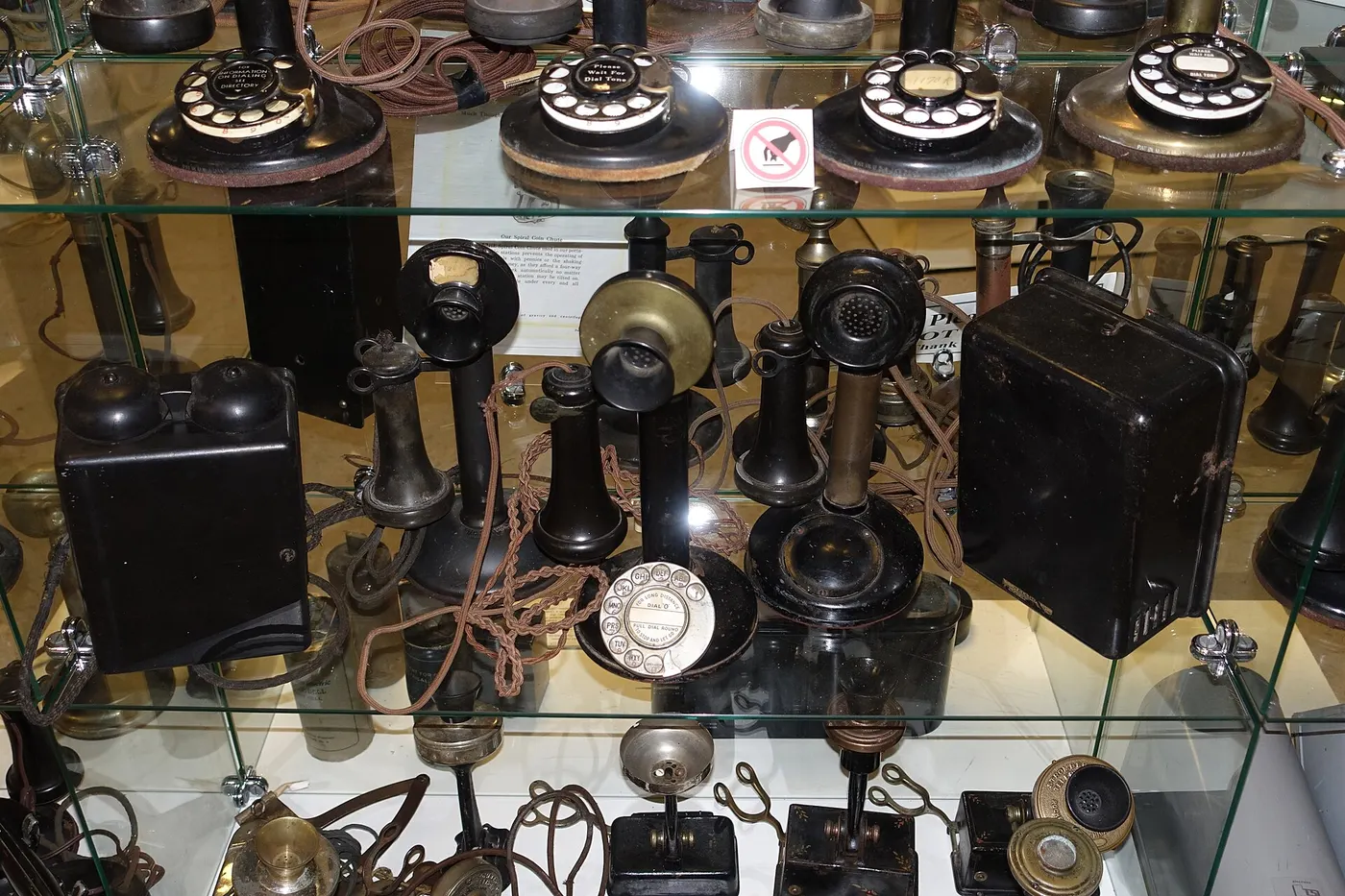 A museum case of early candlestick and rotary telephones